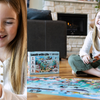 Little girl reading a joke from the back o fa puzzle piece, and then laughing, while completing the Under the Sea Joke Puzzle